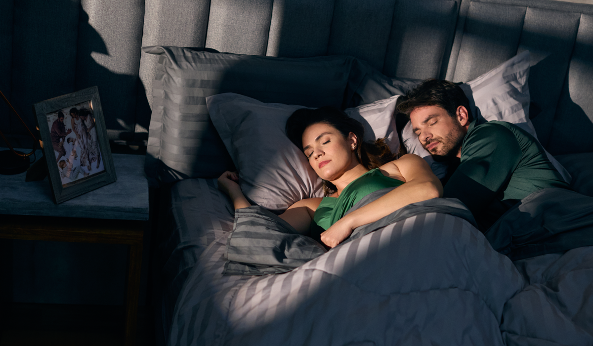 Casal dormindo em uma cama confortável, ilustrando dicas para dormir mais cedo e melhorar a rotina de sono