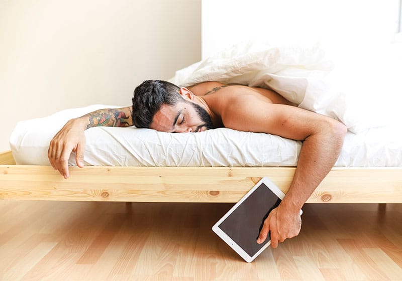 Homem dormindo com um tablet e braço esticado
