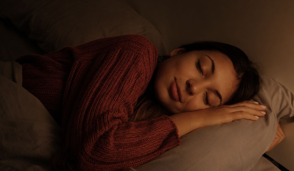 Mulher dormindo tranquilamente em quarto aconchegante, ilustrando o tema por que sonhamos e a relação dos sonhos com o sono