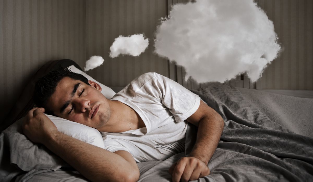 Homem dormindo com balão de sonho acima da cama, ilustrando tipos de sonhos significados e a relação dos sonhos com o sono