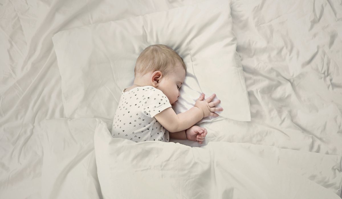 Bebê recém-nascido dormindo em cama clara, ilustrando cuidados sobre travesseiro para recém-nascido e como escolher com segurança