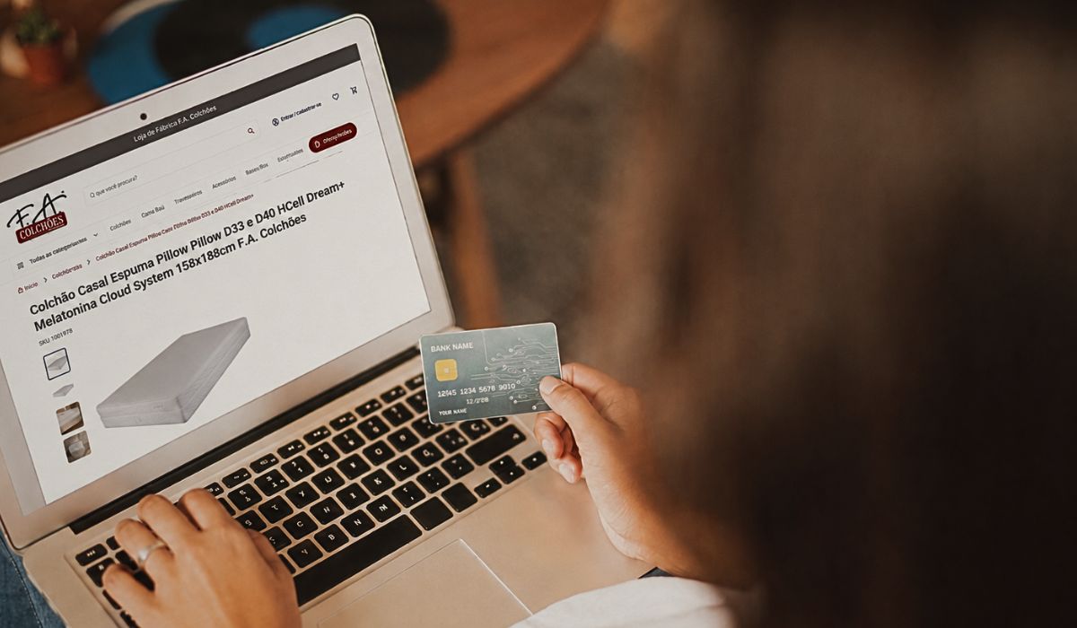 Pessoa comprando colchão pela internet no site da F.A. Colchões, usando notebook e cartão de crédito