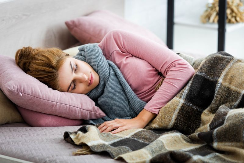 mulher dorme com roupas de frio e coberta quentinha.