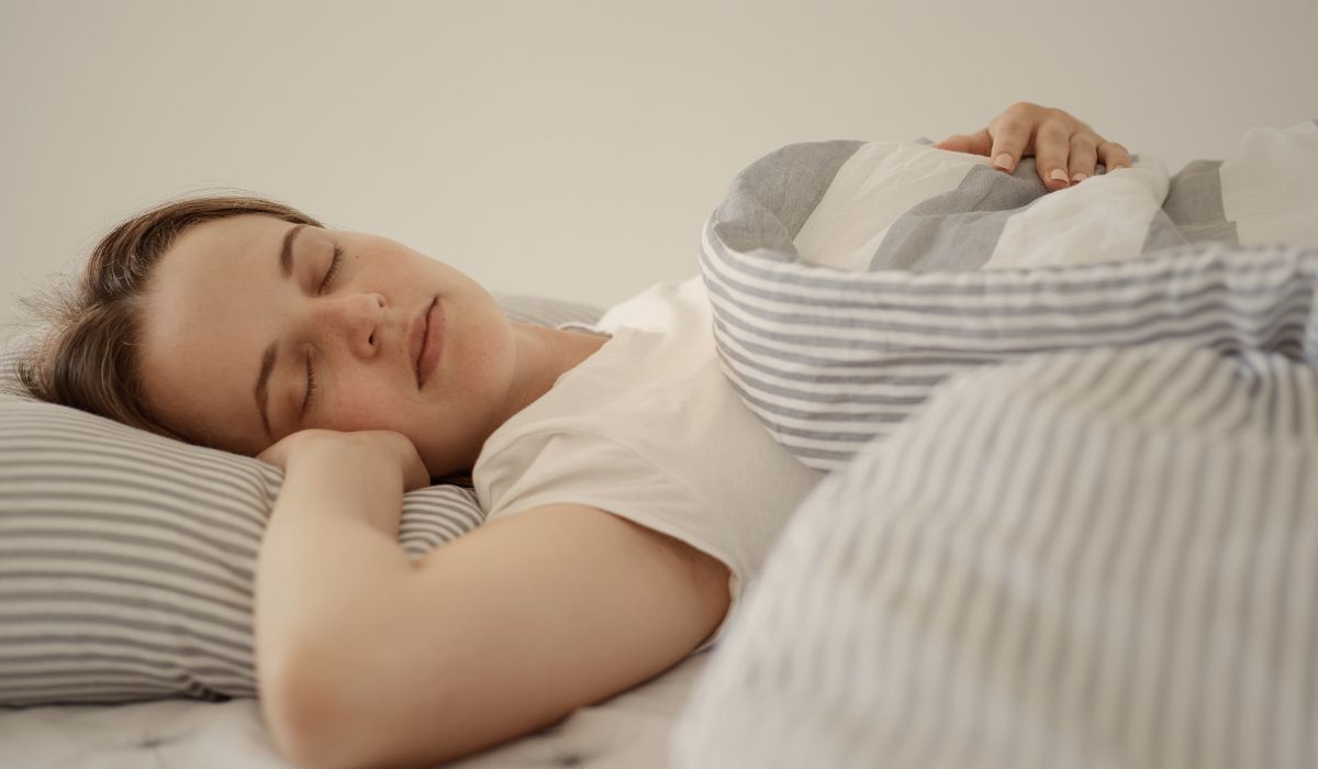 Mulher dormindo tranquilamente na cama, ilustrando o que acontece com o corpo quando dormimos e os benefícios do sono para a saúde