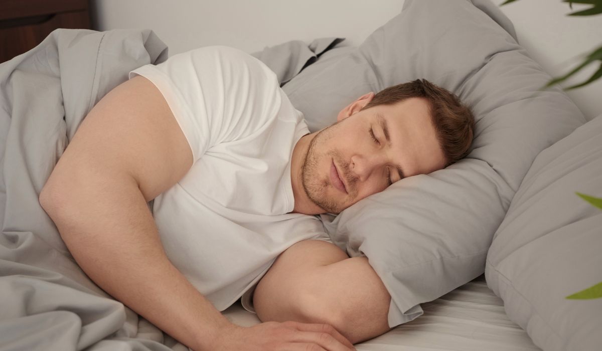 Homem dormindo de lado em cama confortável, ilustrando a dúvida se dormir 6 horas é suficiente para descansar bem.