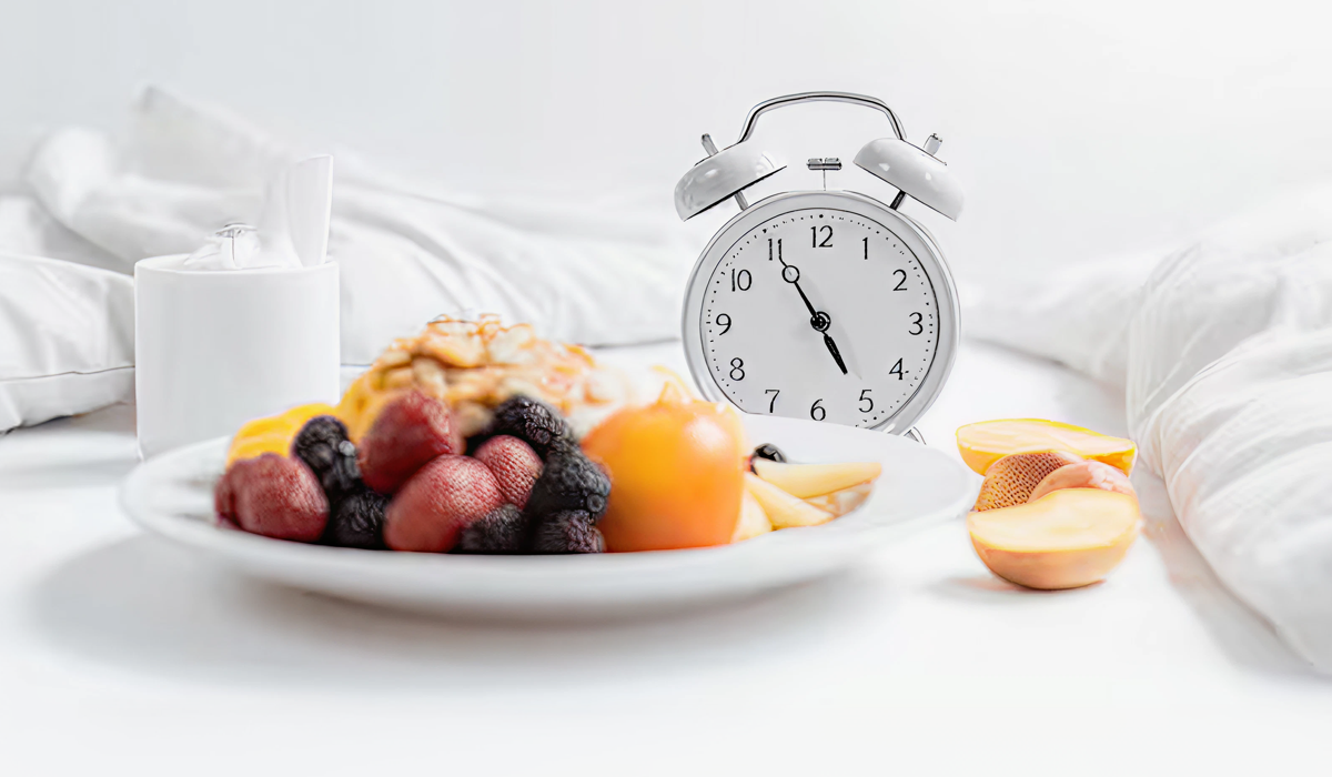 Bandeja com frutas, saladas e vegetais sobre a cama, representando alimentos que dão sono e ajudam no relaxamento antes de dormir.