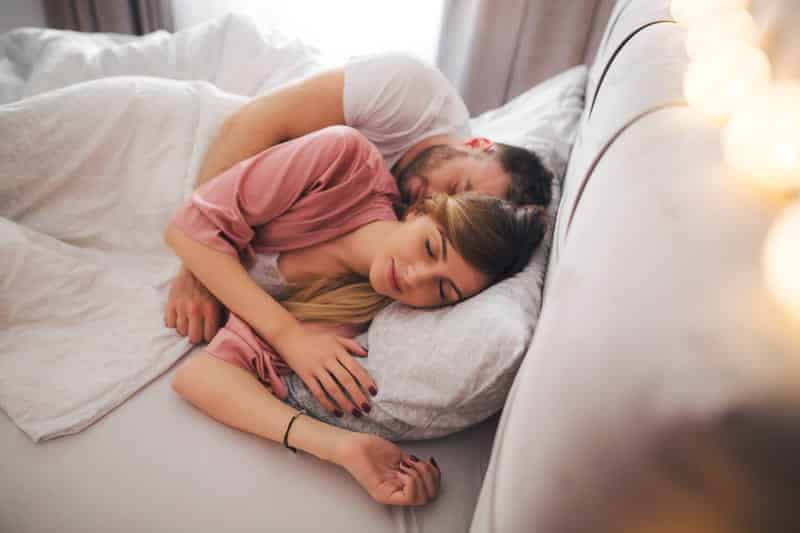 Homem e mulher dormindo de conchinha