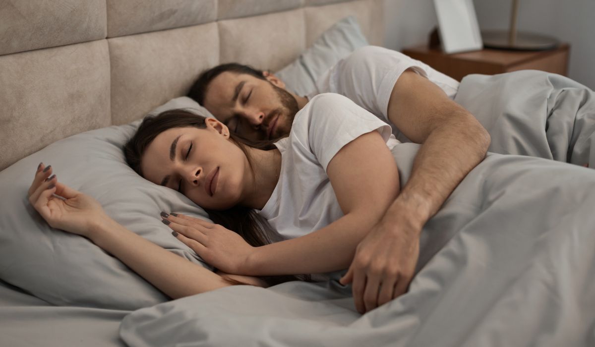 Casal dormindo de conchinha em cama confortável, ilustrando se dormir de conchinha faz bem para o vínculo, relaxamento e qualidade do sono.