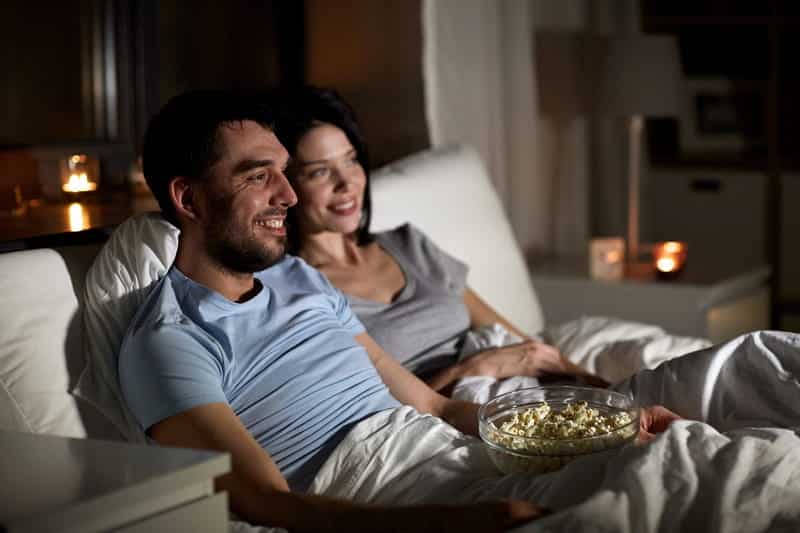 Homem e mulher assistem filme enquanto comem pipoca