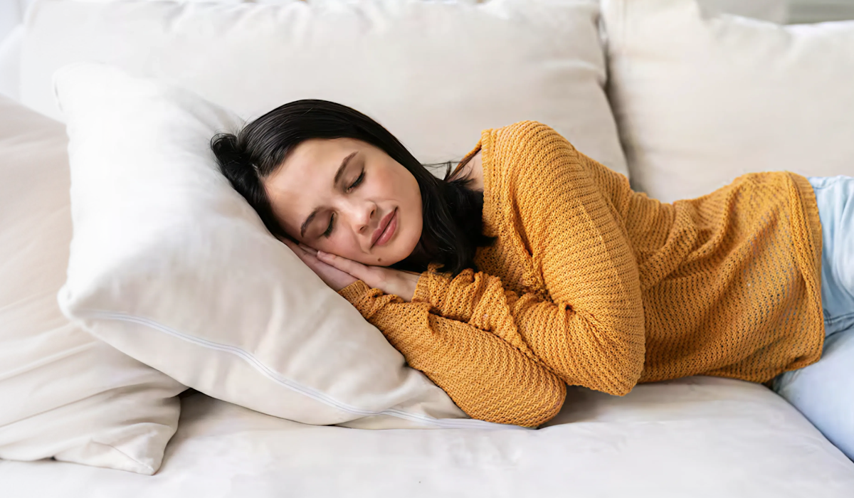Mulher cochilando confortavelmente sobre travesseiro branco, ilustrando o tempo ideal de cochilo para recuperar energia durante o dia