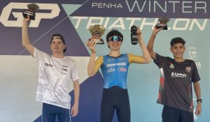 Atletas no pódio segurando troféus em competição de triathlon, ilustrando o projeto F.A. Apoia: Alejandro Juanuk.
