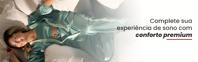 Mulher relaxando deitada em travesseiros confortáveis com expressão de bem-estar, destacando experiência de sono premium