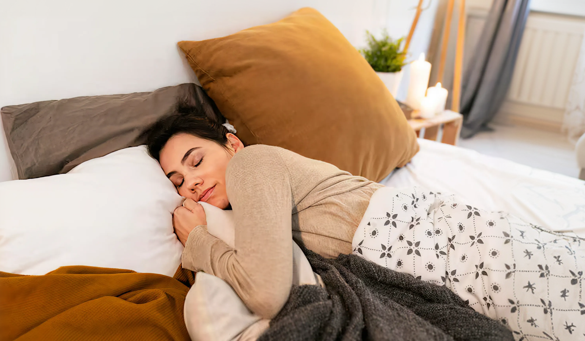 Mulher dormindo confortavelmente em cama aconchegante com cobertores e almofadas, ilustrando conforto para dormir no inverno.