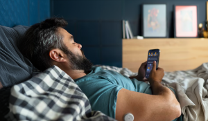 Pessoa deitada na cama usando o celular e acompanhando dados do sono no aplicativo, em um quarto aconchegante, representando o monitoramento dos sonhos e da qualidade do descanso.